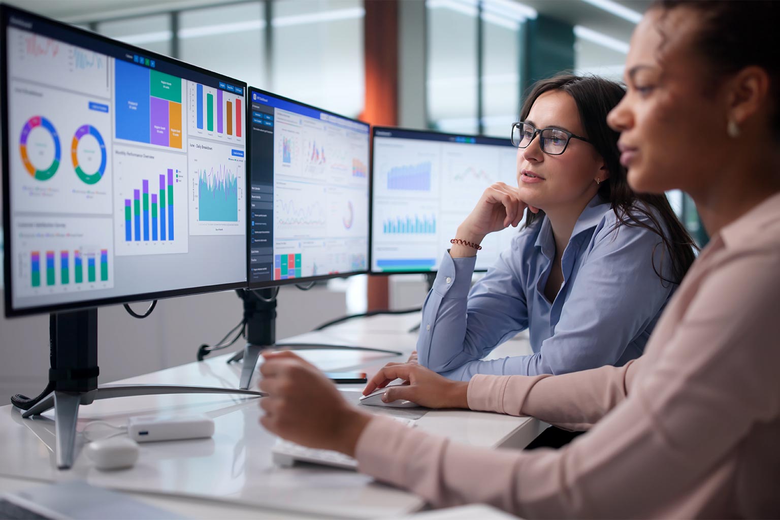 Two colleagues reviewing performance dashboards on multiple monitors, the reporting a lean IT team uses to plan capacity